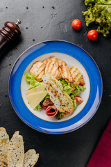 Grilled chicken salad with cheese slices, bacon, lettuce, and crispy bread for a hearty, fresh meal