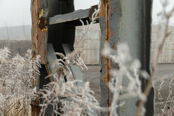 Rusty metal construction in an abandoned industrial zone covered in winter fog and frost