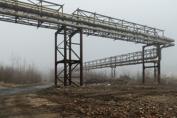 Overhead tubes and pipes in an abandoned industrial zone on a foggy winter day