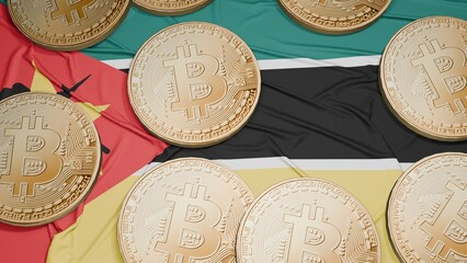Several bitcoins are laid out on the flag of Mozambique