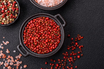 Spice, allspice peas in red or pink color in a bowl on a black concrete background