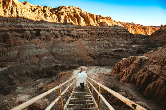 Woman is hiking down a staircase into a canyon at Cathedral Gorge State Park, Panaca, Lincoln County, Nevada, USA