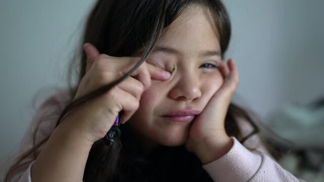 Tired little girl rubbing eye with finger, exhausted weary female child feeling fatigue late at night close-up face