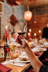 Raising a glass of red wine during a festive dinner celebration with candles and elegant decor