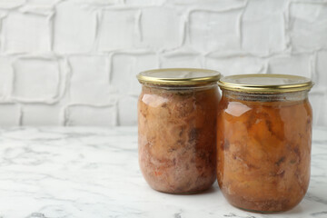 Canned meat in glass jar on white marble table, space for text