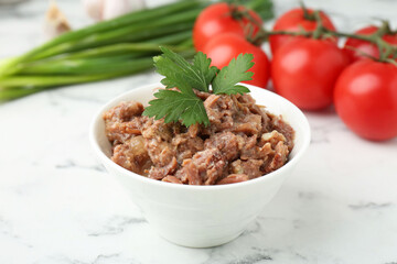 Canned meat in bowl, parsley, tomatoes and green onions on white marble table, closeup