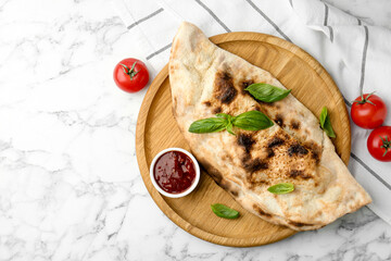 Delicious calzone served on white marble table, top view. Space for text