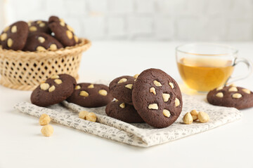 Tasty chocolate cookies with hazelnuts and tea on white table, closeup