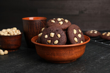Tasty chocolate cookies with hazelnuts on black table, closeup