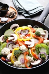 Frying pan with mix of vegetables, mushrooms and spices on table, closeup