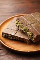 Pieces of tasty Dubai chocolate with pistachios and knafeh on wooden table, closeup