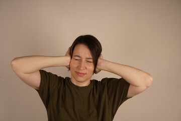 The person contorted his face from a severe headache. Near the gray wall.