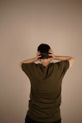 The girl turned away from the camera to the gray wall and covered her ears. She shows the back of...