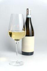 Glass of Red Wine with Bottle in Background on White.