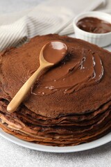 Delicious chocolate crepes with sweet paste on light grey table, closeup