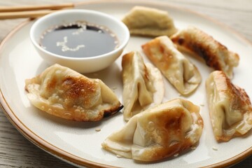 Fried gyoza dumplings with soy sauce on wooden table, closeup