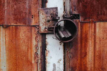 Old aged metal gate closed front view. Rusty doors with paint peeled out close up view. Closed private area. Abstract red brown metal sheet, panel.