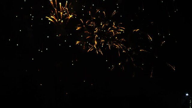 gold red orange sparks scattering fireworks on the black night sky. General plan