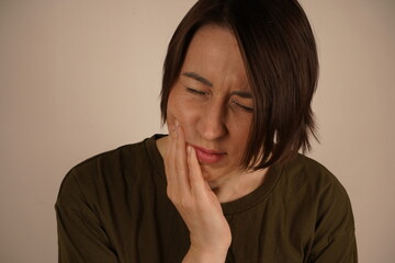 Very tired stressed young business woman standing near the wall. Holding a hand on the shock and...
