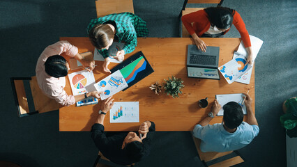 Top down view of manager holds tablet display increasing sales and placed on meeting table. Group of diverse business team clapping hands to celebrate successful product at meeting room Convocation.