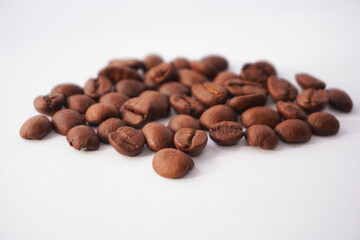 A close-up view of roasted coffee beans spread on a white background, showcasing their dark brown color smooth texture, and intricate details, emphasizing their natural richness and organic appearance