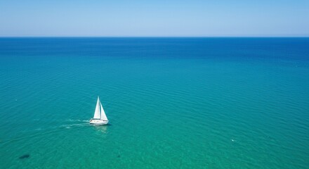 A white boat gliding through vibrant teal and blue ocean waters under a clear blue sky.
