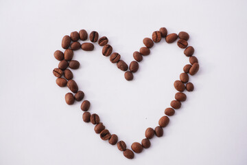 A heart shape carefully arranged with roasted coffee beans on a white background, creating a minimalist and artistic composition that symbolizes love, warmth, and appreciation for coffee.