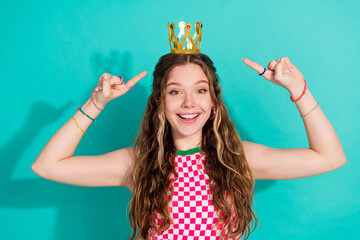 Portrait of pretty young girl point fingers crown wear plaid dress isolated on turquoise color...