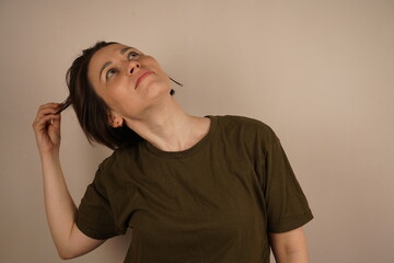 Sad dark-haired girl holding her damaged hair, looking away from the camera.