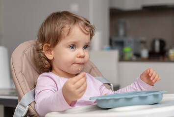A curious toddler concentrating on self-feeding during a calm mealtime.