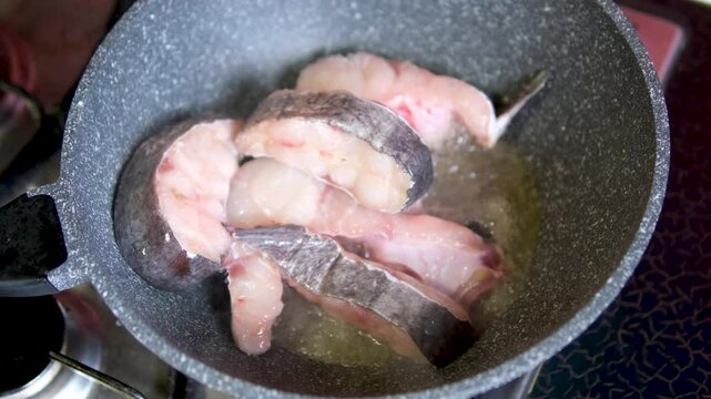 A cod fish steak frying in a frying pan close-up. Cooking fish in the hot oil at restaurant. High quality 4k footage