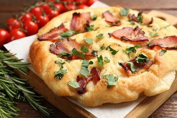 Delicious focaccia bread with bacon and parsley on wooden table, closeup