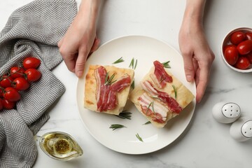 Woman serving delicious focaccia bread at white table, top view