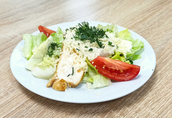 Delicious salad with grilled chicken, lettuce, rice, and fresh tomatoes served on a plate