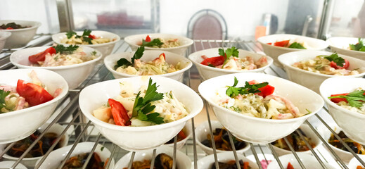 Colorful bowls of fresh salad displayed in a restaurant kitchen during lunchtime preparation