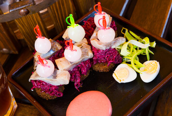 Appetizer of homemade pickled herring with onions, grated beets served on toasted black bread. Russian cuisine