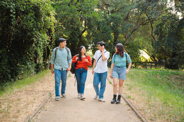 Fototapeta premium Group of four happy students with backpacks in the park