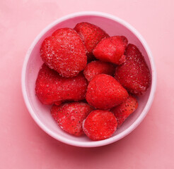 bowl of frozen strawberries on pink background