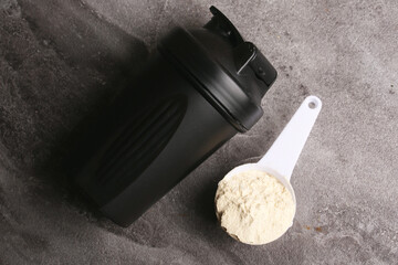 shaker and spoon of protein on light background