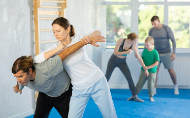 Woman in gym perform basic elements of krav maga self-defense system, sparring with male teacher. Preparation of athletes before competitions