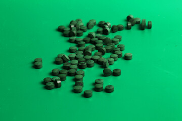 spirulina tablets on green background
