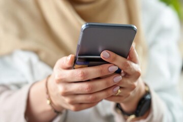 Close view of woman's hands holding a phone and a credit card