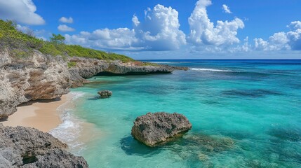 Obraz premium Secluded tropical beach with turquoise water, white sand, and rocky cliffs under a bright blue sky.