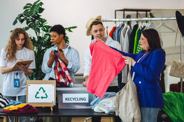 Fototapeta premium Young woman brings old clothes for recycling, charity, donation. Volunteers sorting textile to prevent pollution, environment protection. Second hand shopping. Eco conscious responsible lifestyle.