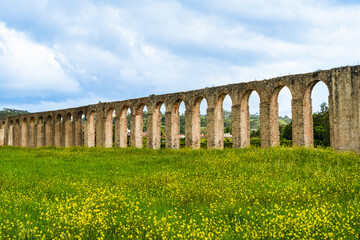 Obraz premium Obidos, Portugal: Obidos Aqueduct beyound a field of yellow flowers; 16th-century aqueduct built at the orders of Catherine of Austria in around 1570