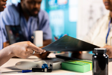 African american general practitioner leading a junior medical team in office, analyzing x ray imaging results and providing accurate diagnosis. Nurses and physician at medical facility.