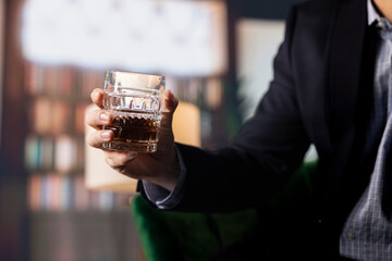 Two partners drinking glass of whiskey in the social club library, discuss career goals and perspectives to double fortune. Upper class elite gentlemen serving scotch and do business. Close up.