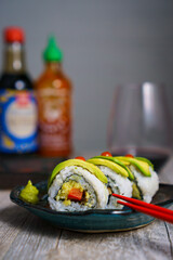 Assorted sushi platter featuring California rolls, avocado sushi, and spicy rolls with hot sauce, beautifully arranged to highlight fresh ingredients and vibrant textures perfect for culinary websites