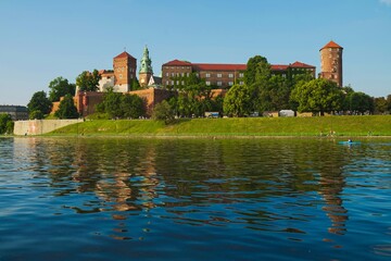 Obraz premium Historic Wawel Castle reflected in the Vistula River during a sunny day in Krakow