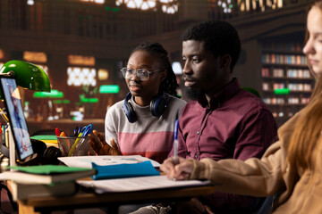 University students in a library use online video conferencing to attend a telehealth class, discussing microbiology and medical techniques to practice later with a specialist. Medical academy.